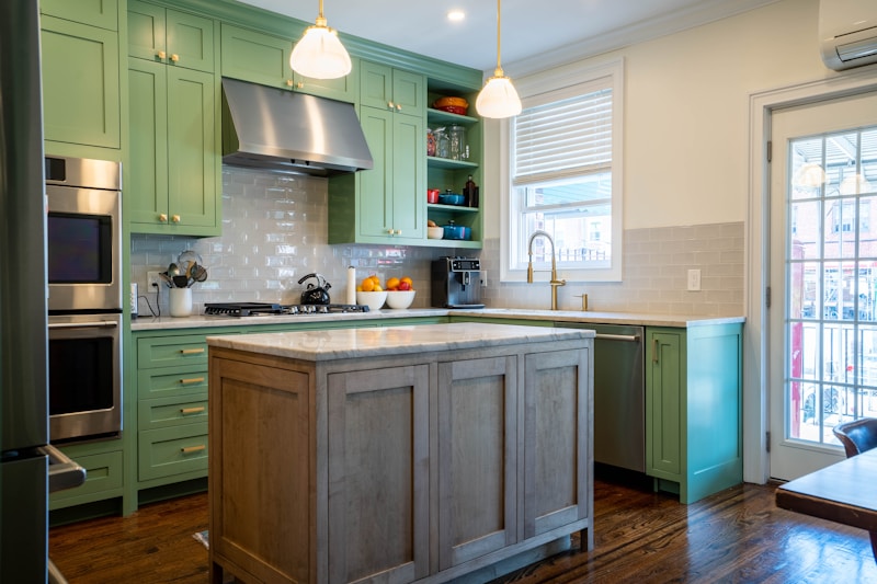 A kitchen island and run of cupboards in deep estate green
